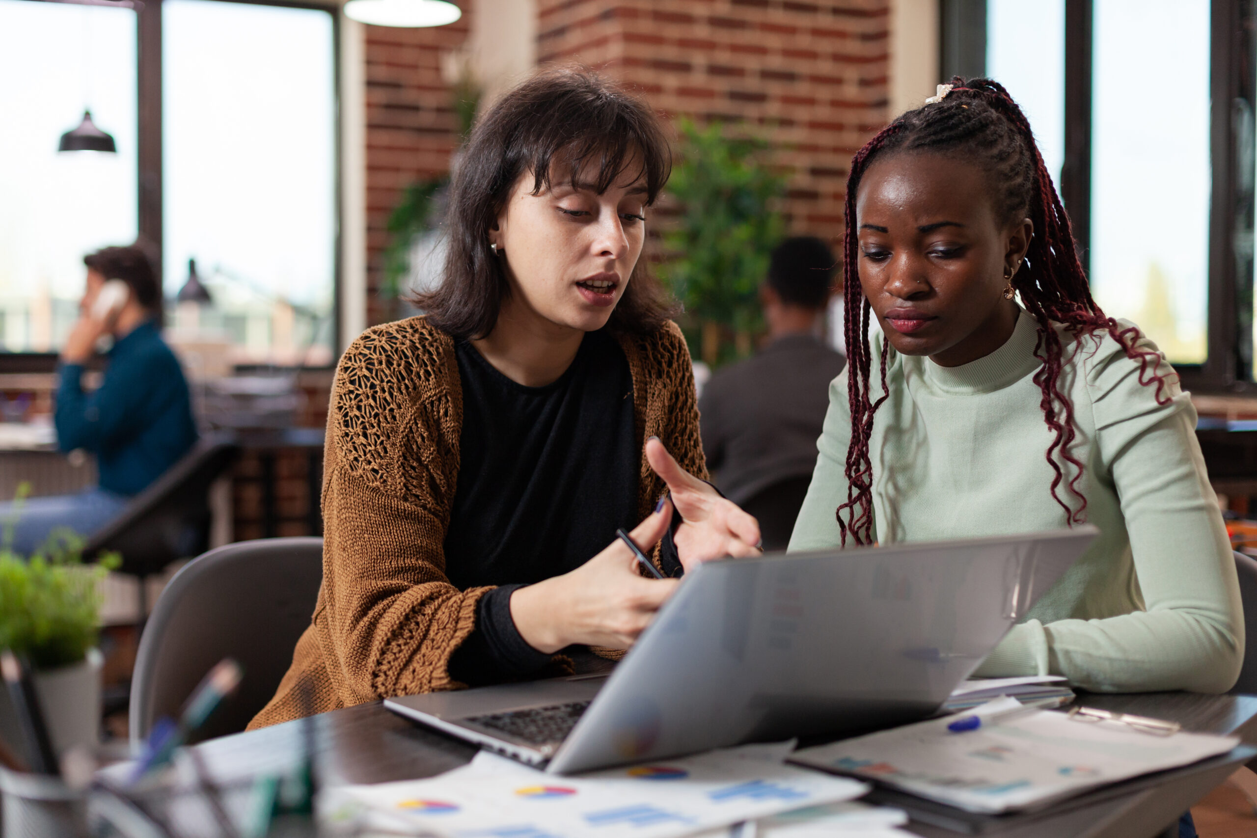 Multiracial businesswomen working at financial project analyzing marketing graphs on computer in startup office. Diverse team discussing company turnover planning business collaboration
