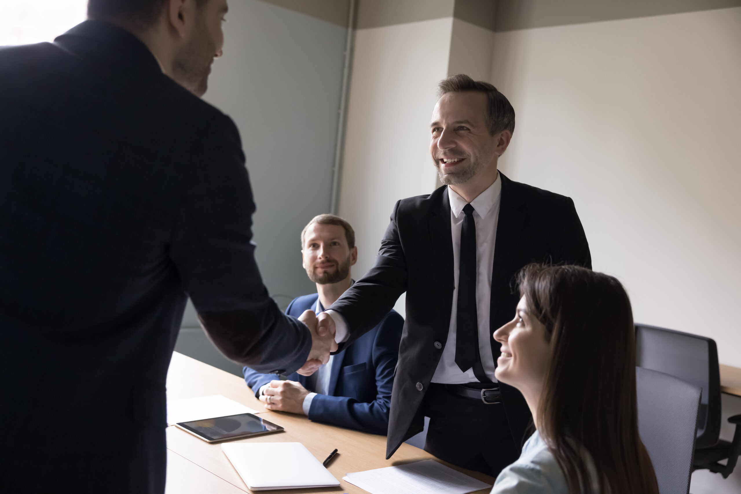 Confident positive male leader shake hands new employee standing in modern office, congratulate with promotion, successful businesspeople greeting each other at business meeting, make financial deal